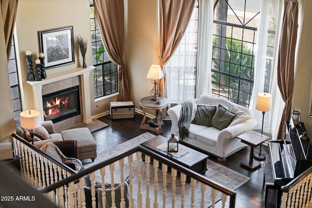 living area featuring hardwood / wood-style floors, baseboards, and a tiled fireplace
