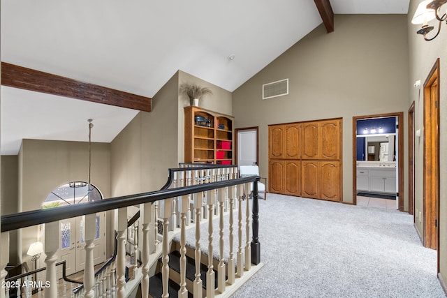 hallway featuring high vaulted ceiling, beamed ceiling, and light colored carpet