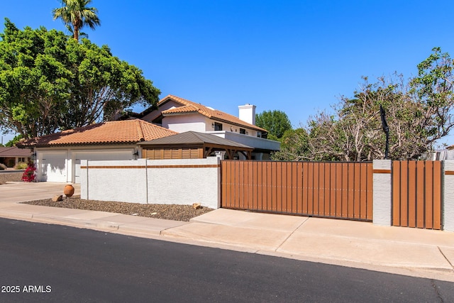 view of front of home featuring fence, driveway, a tiled roof, an attached garage, and stucco siding