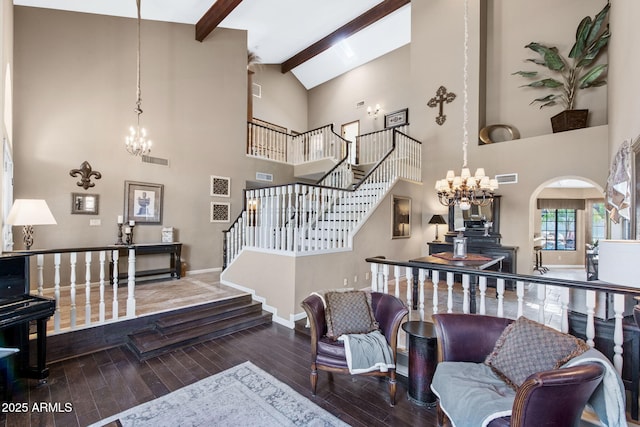 living area with a chandelier, hardwood / wood-style floors, beamed ceiling, high vaulted ceiling, and stairway
