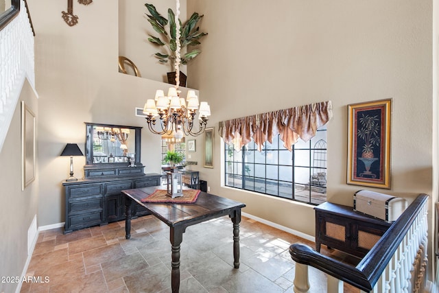 office space featuring baseboards, a high ceiling, a chandelier, and stone tile floors