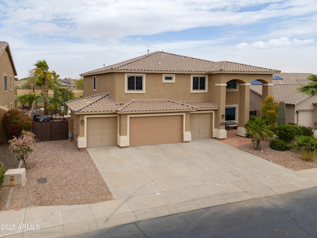 mediterranean / spanish house with fence, concrete driveway, a tile roof, stucco siding, and a garage