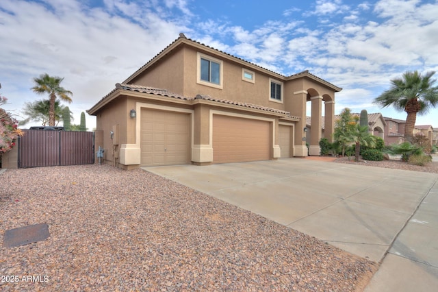 mediterranean / spanish house featuring an attached garage, fence, a tiled roof, stucco siding, and driveway