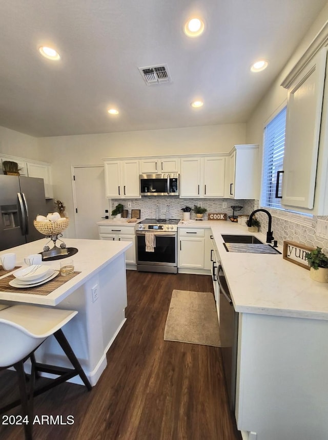 kitchen featuring light stone countertops, appliances with stainless steel finishes, dark wood-type flooring, sink, and white cabinetry