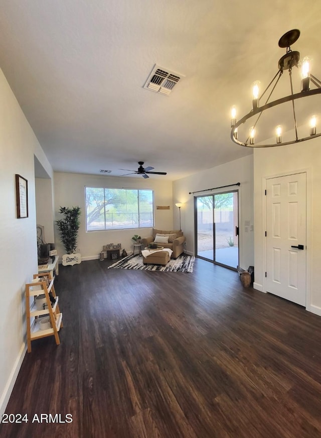 living room with ceiling fan with notable chandelier and dark hardwood / wood-style flooring