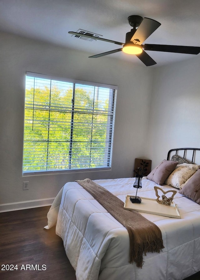 bedroom featuring multiple windows, dark hardwood / wood-style floors, and ceiling fan