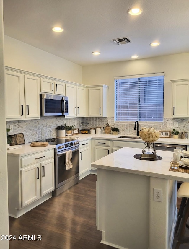 kitchen with sink, dark hardwood / wood-style flooring, a breakfast bar area, white cabinets, and appliances with stainless steel finishes