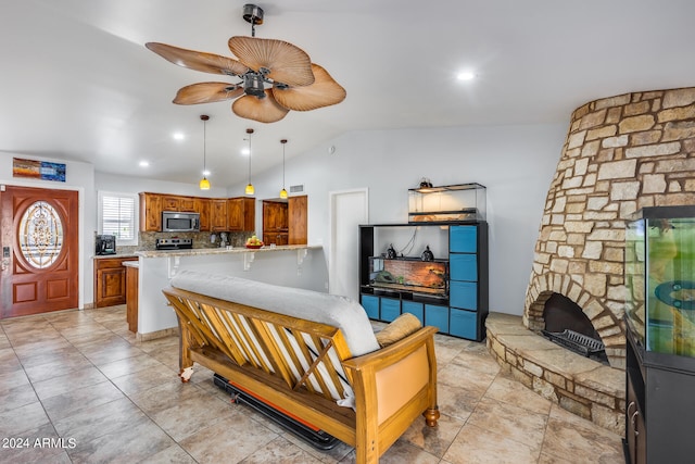 living room featuring ceiling fan, a fireplace, and vaulted ceiling