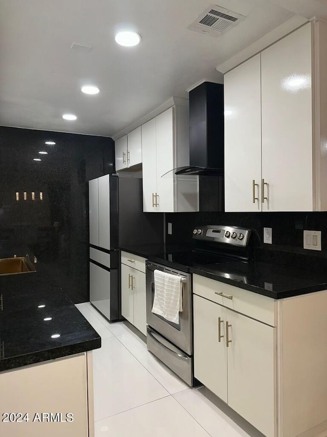 kitchen featuring wall chimney exhaust hood, light tile patterned floors, tasteful backsplash, white cabinetry, and stainless steel appliances