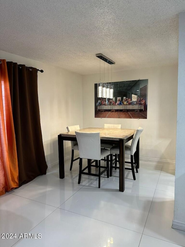 dining space featuring a textured ceiling and tile patterned floors