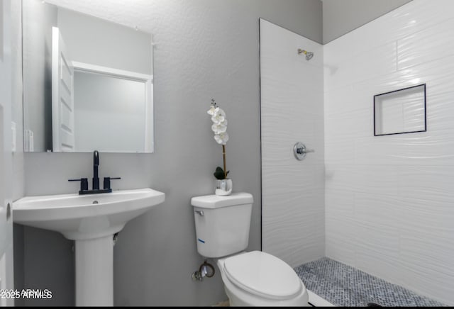 bathroom with toilet and tiled shower