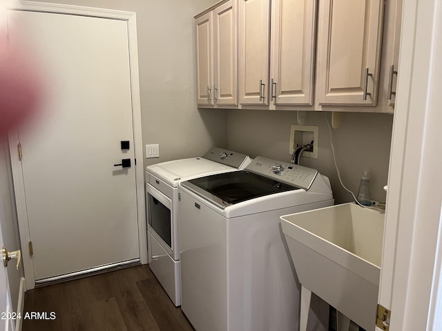 washroom featuring washing machine and clothes dryer, sink, cabinets, and dark hardwood / wood-style floors