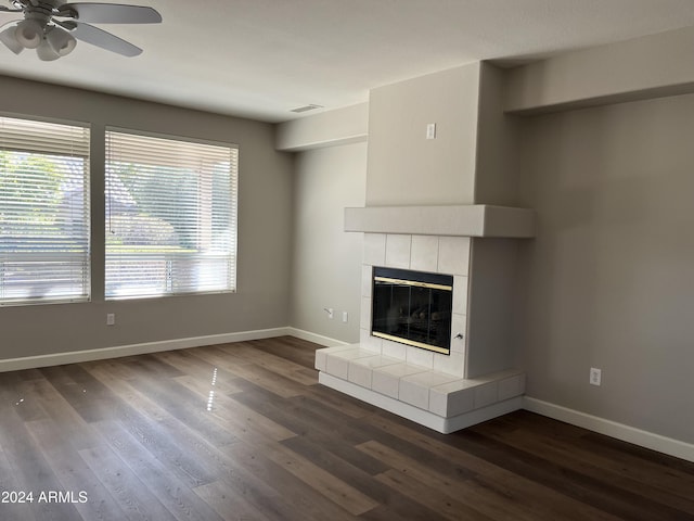 unfurnished living room with dark hardwood / wood-style floors, ceiling fan, and a tile fireplace