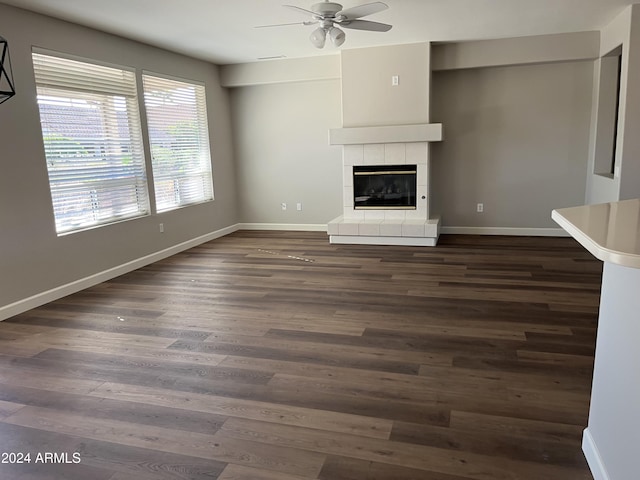 unfurnished living room featuring ceiling fan, a fireplace, and dark hardwood / wood-style floors