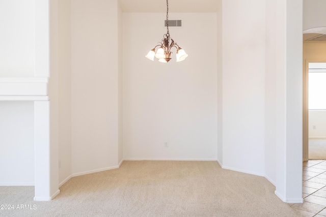 empty room featuring light carpet and a notable chandelier