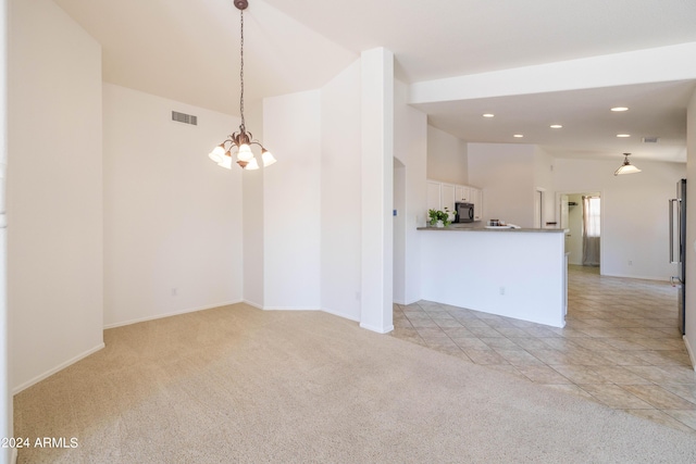 carpeted empty room featuring a notable chandelier and vaulted ceiling