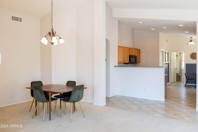 dining area featuring a towering ceiling, an inviting chandelier, and light colored carpet