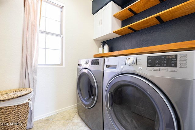 clothes washing area with cabinets, independent washer and dryer, and light tile patterned flooring