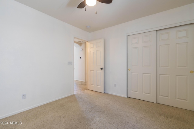 unfurnished bedroom with light colored carpet, a closet, and ceiling fan