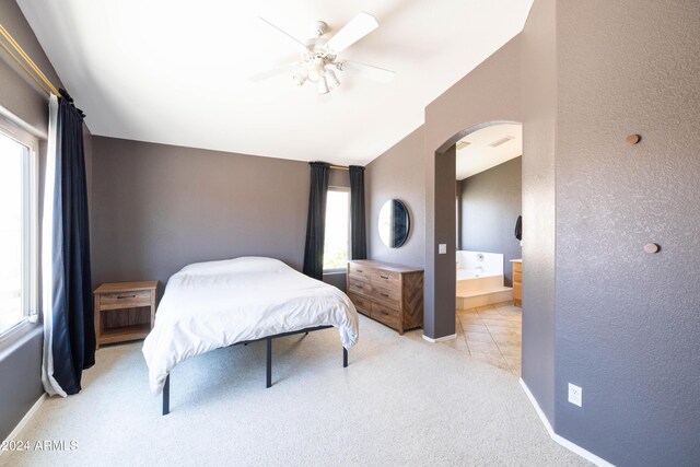 bedroom featuring ceiling fan, ensuite bathroom, light carpet, and lofted ceiling