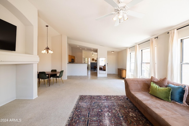 living room with light carpet, ceiling fan with notable chandelier, and a wealth of natural light