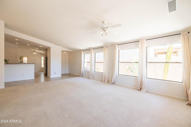 spare room with ceiling fan, lofted ceiling, and light carpet