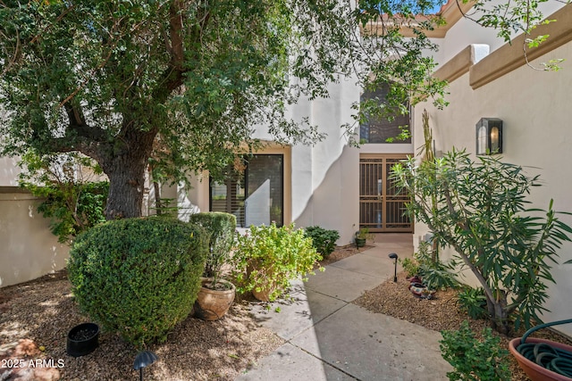 property entrance with fence and stucco siding