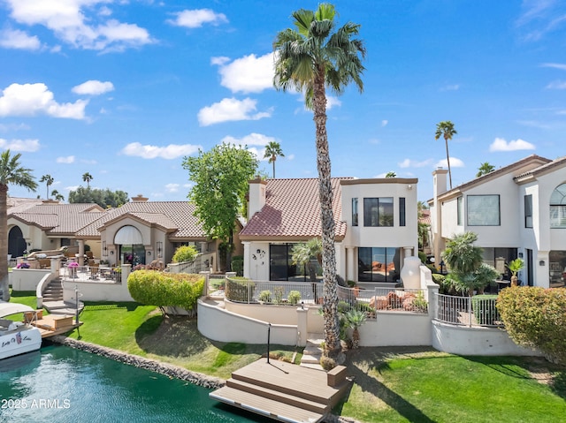 rear view of property with a water view, a tile roof, a residential view, stucco siding, and a chimney