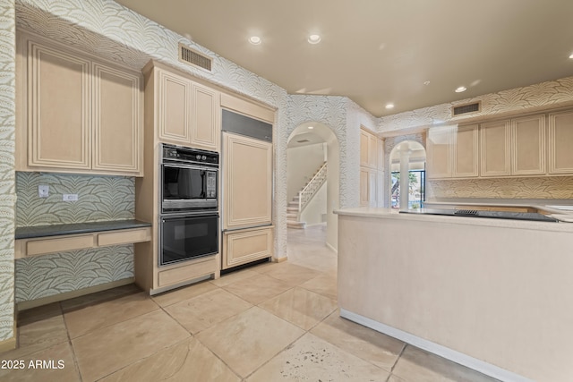 kitchen with dobule oven black, visible vents, paneled refrigerator, and arched walkways