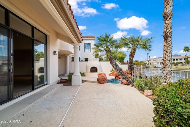 view of patio with fence and exterior fireplace