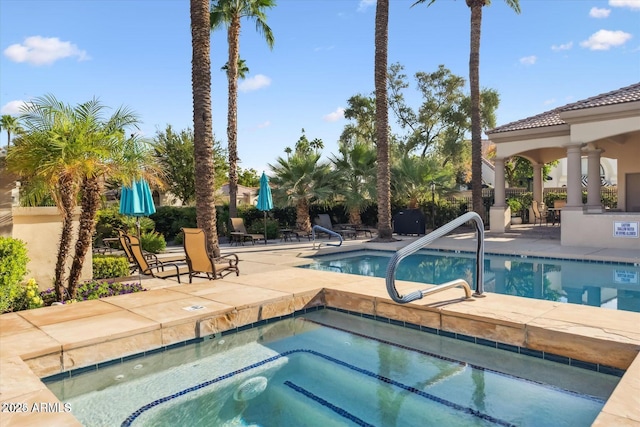 community pool featuring a patio area, fence, and a hot tub