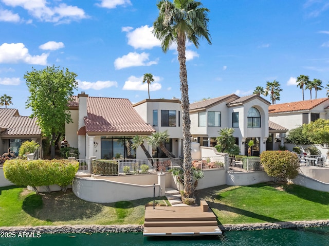 rear view of property with a tiled roof, a chimney, a water view, and stucco siding