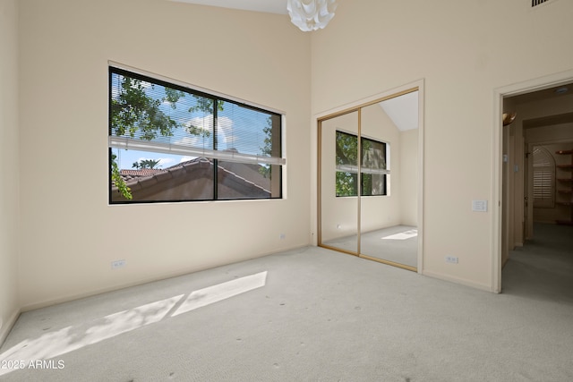 unfurnished bedroom featuring a closet, a high ceiling, multiple windows, and carpet flooring