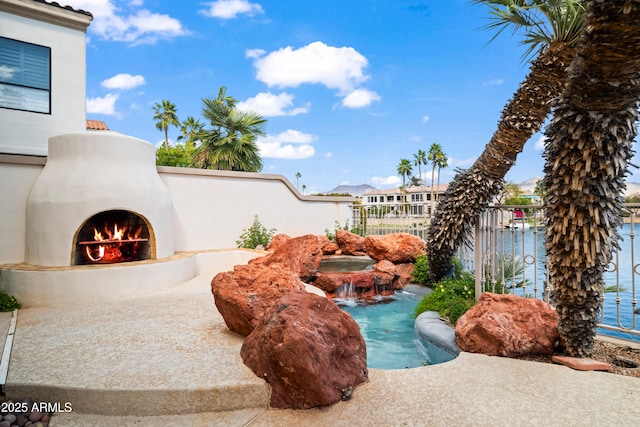 exterior space featuring a warm lit fireplace and fence