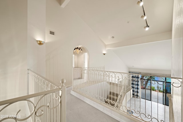 hallway with high vaulted ceiling, carpet, visible vents, and track lighting