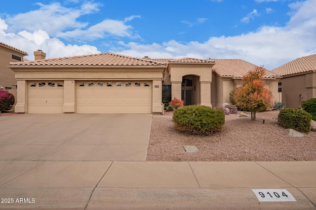 mediterranean / spanish home with an attached garage, driveway, a tile roof, and stucco siding