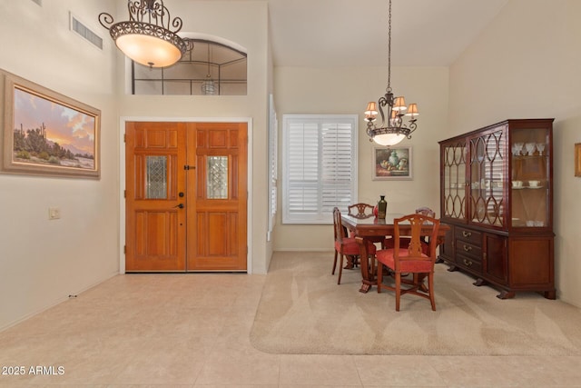 entryway featuring visible vents, a notable chandelier, and a towering ceiling