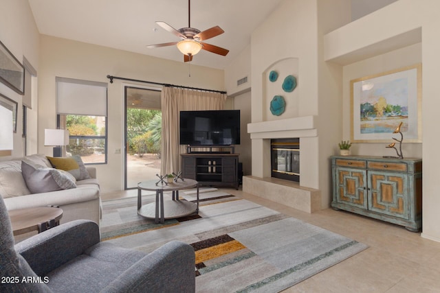 living room featuring visible vents, ceiling fan, a premium fireplace, tile patterned floors, and high vaulted ceiling