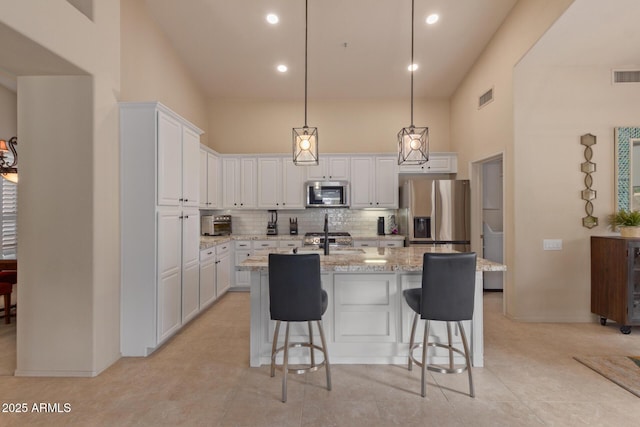 kitchen with white cabinets, visible vents, stainless steel appliances, and backsplash