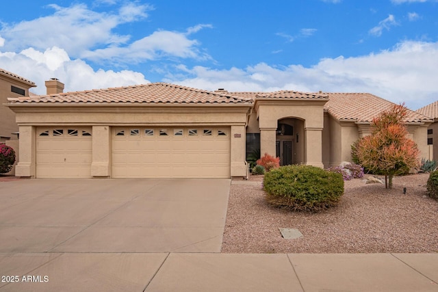 mediterranean / spanish-style house with driveway, a chimney, a tiled roof, an attached garage, and stucco siding