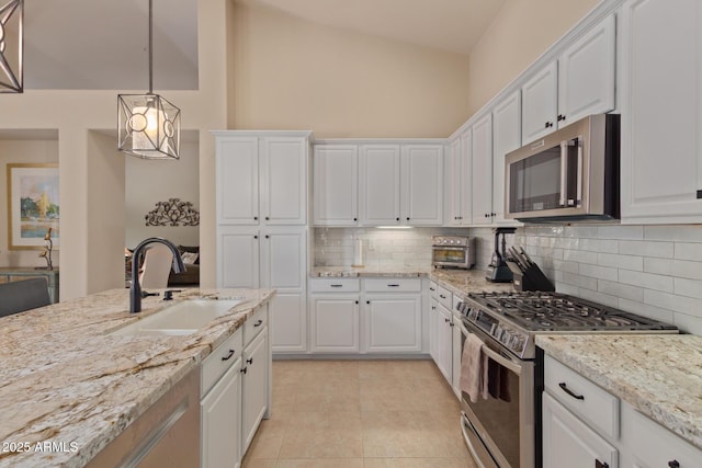 kitchen with stainless steel appliances, tasteful backsplash, a sink, and white cabinetry