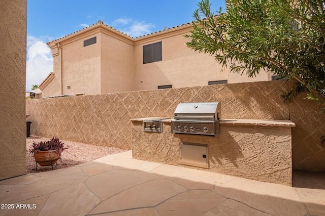 view of patio with area for grilling, a grill, and fence