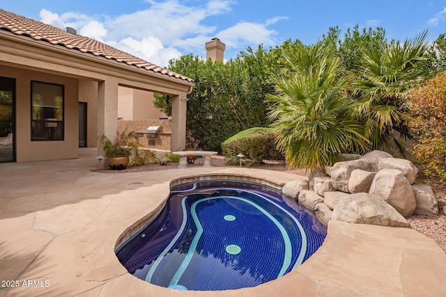 view of swimming pool featuring a patio area, an outdoor kitchen, and an in ground hot tub