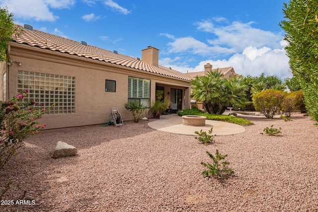 back of house featuring an outdoor fire pit, a tile roof, a chimney, a patio area, and stucco siding