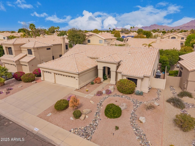 view of front of house with driveway, an attached garage, a tile roof, and fence