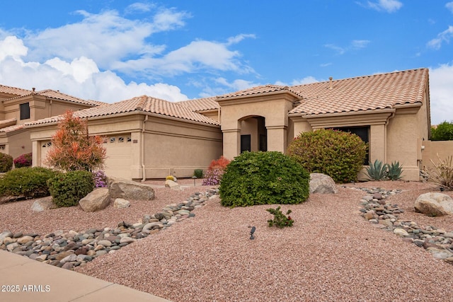 mediterranean / spanish home with a tiled roof, an attached garage, and stucco siding