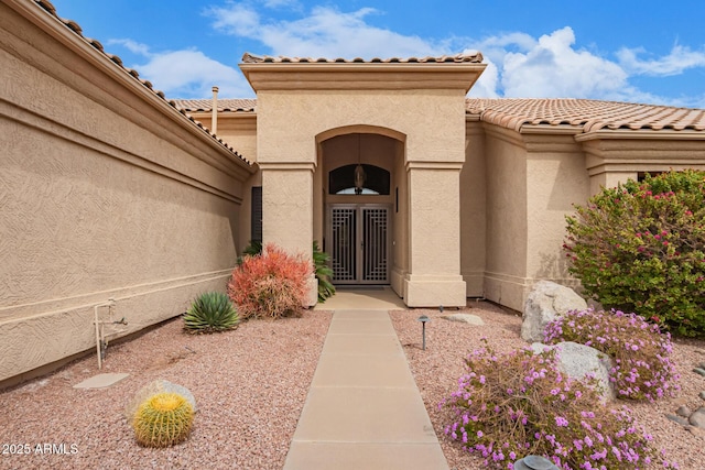 doorway to property featuring a tile roof and stucco siding