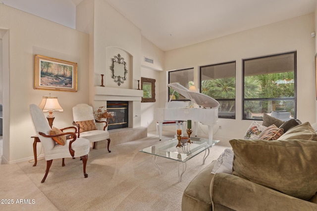 living area with high vaulted ceiling, a glass covered fireplace, visible vents, and baseboards