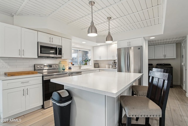 5119 E Shaw Butte Dr, Scottsdale, AZ 85254 - kitchen featuring stainless steel appliances, washer and dryer, a kitchen breakfast bar, backsplash, and light countertops