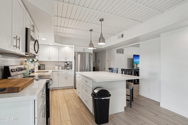5119 E Shaw Butte Dr, Scottsdale, AZ 85254 - kitchen featuring stainless steel appliances, a breakfast bar, tasteful backsplash, white cabinetry, and light countertops